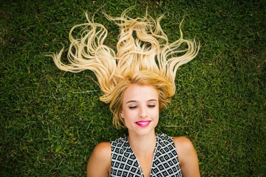 woman with blonde hair lying in grass