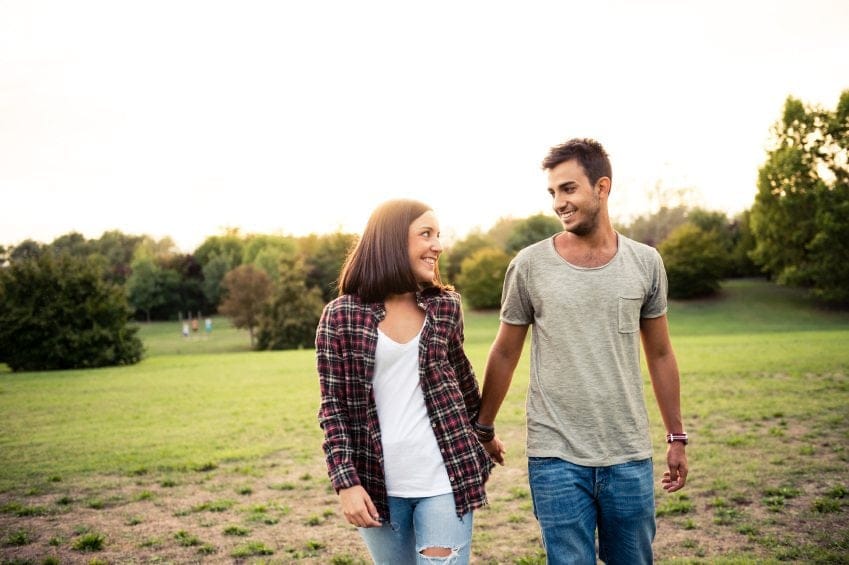 couple holding hands on park walk