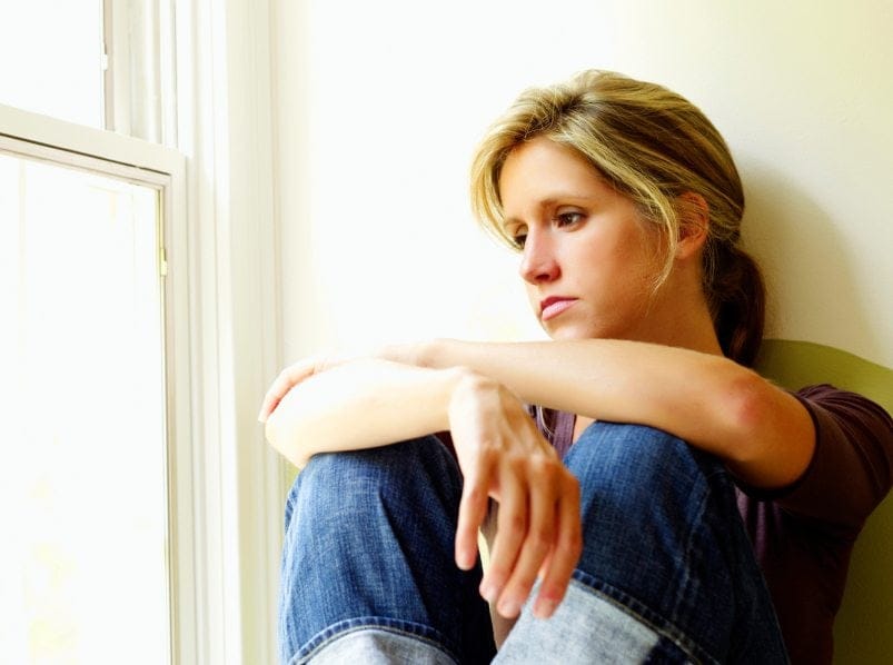 A woman depressed looking out the window.