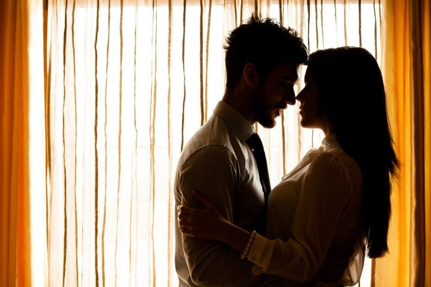 Couple embracing beside window