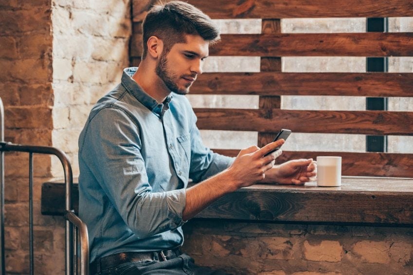 young man texting with coffee