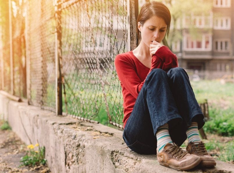 Young woman sat on wall alone
