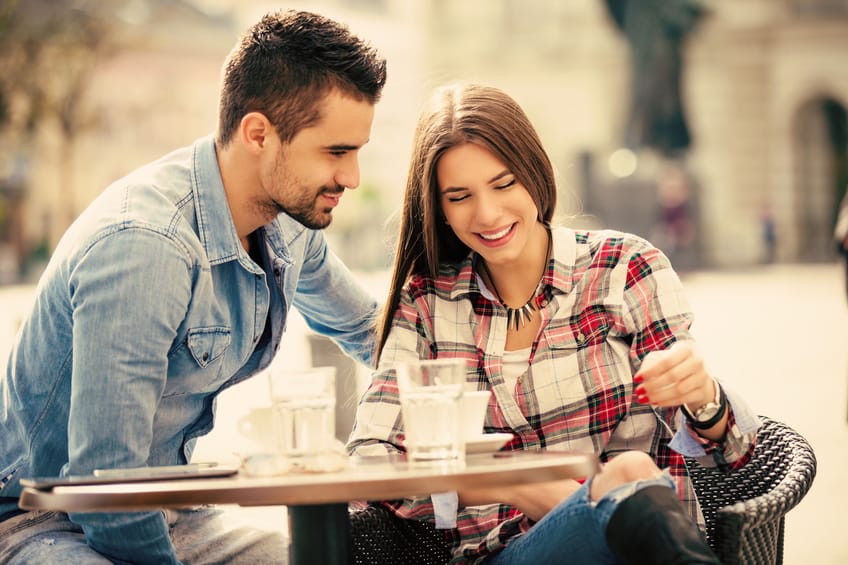 Happy young couple sitting in a cafe outside on a beautiful day.