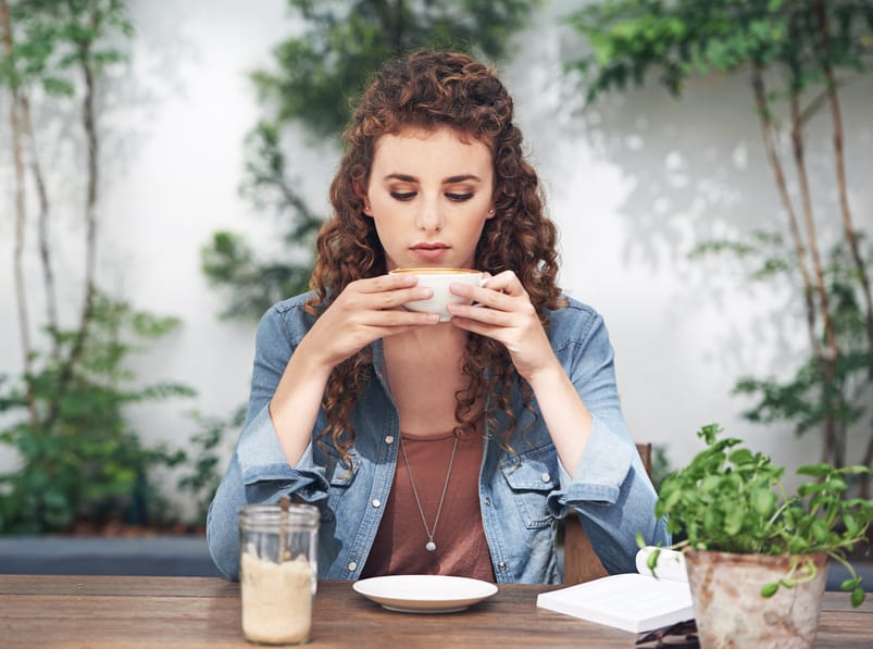 Young curly haired woman drinking coffee
