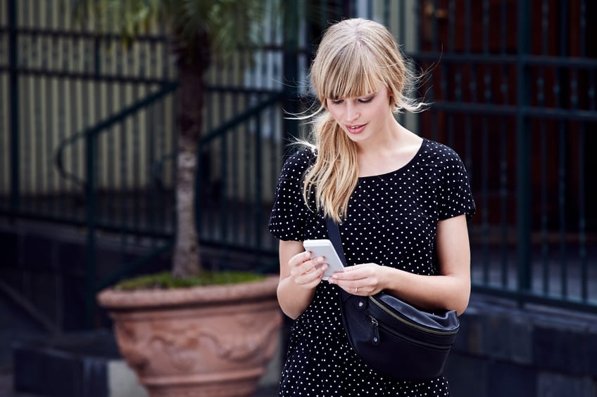 Blond young woman texting on Smartphone