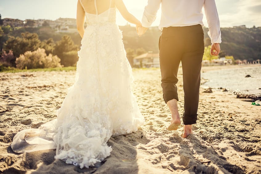 Bride and groom holding hands on the beach at sunset