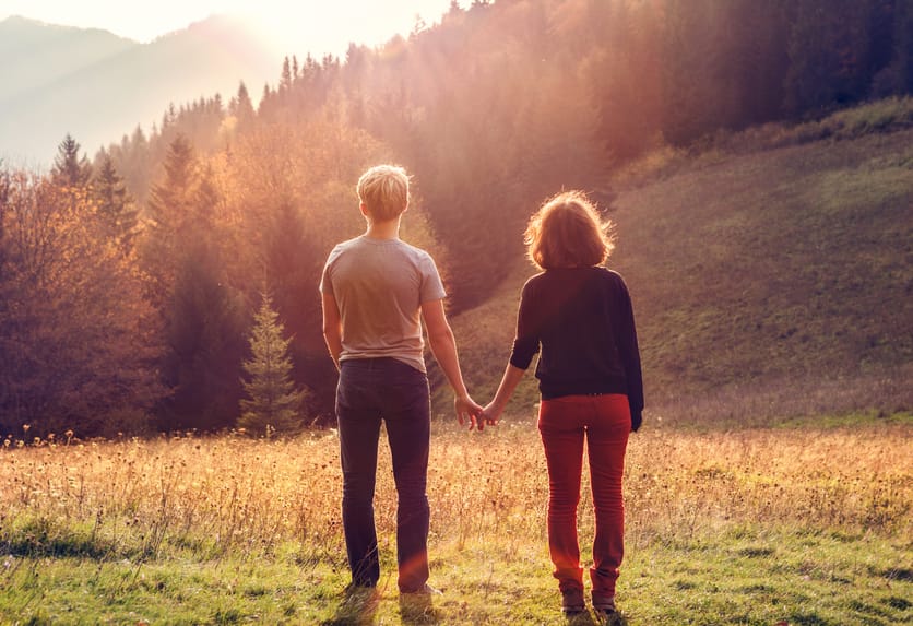 Young couple takes hands in sunset time