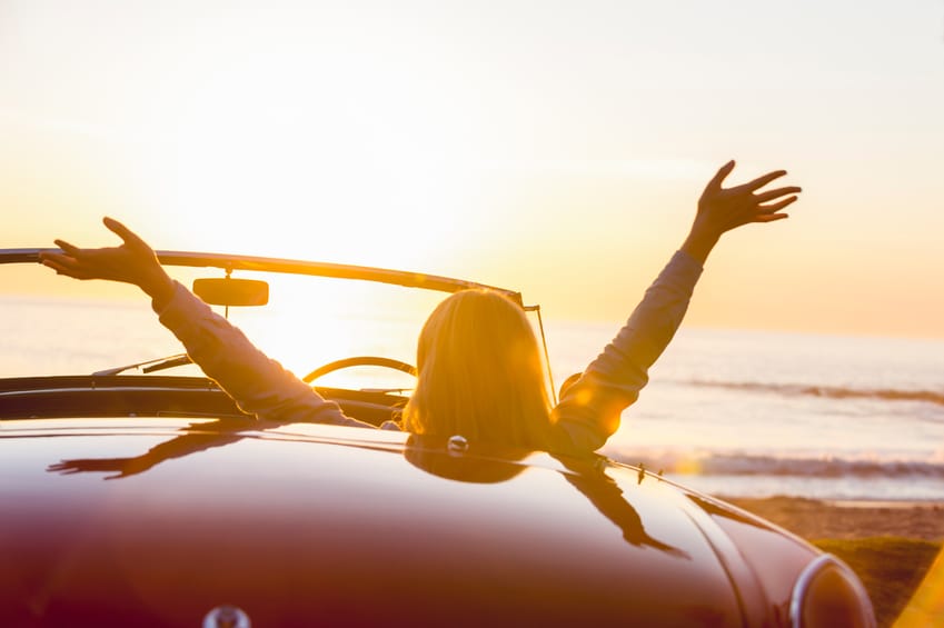 Woman watching the sunset in a convertible car