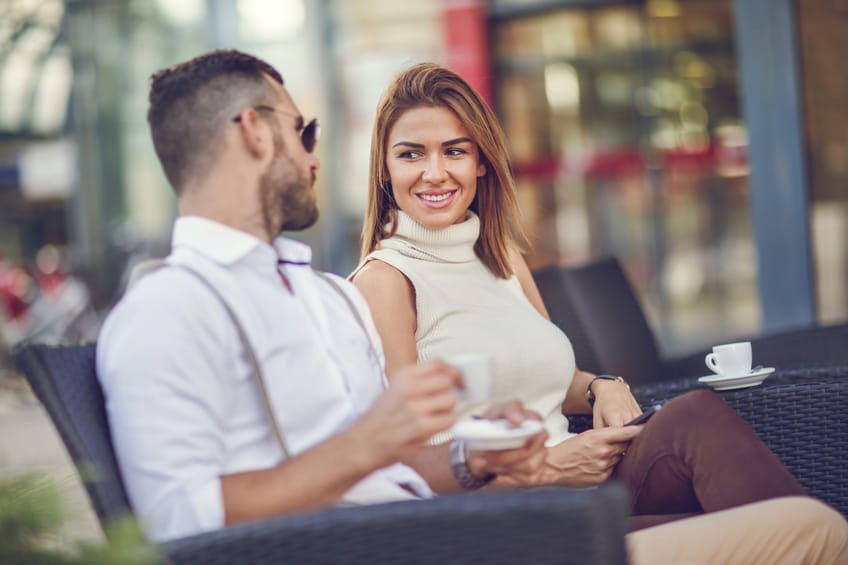 Happy businesswoman talking to her male colleague in a cafe.