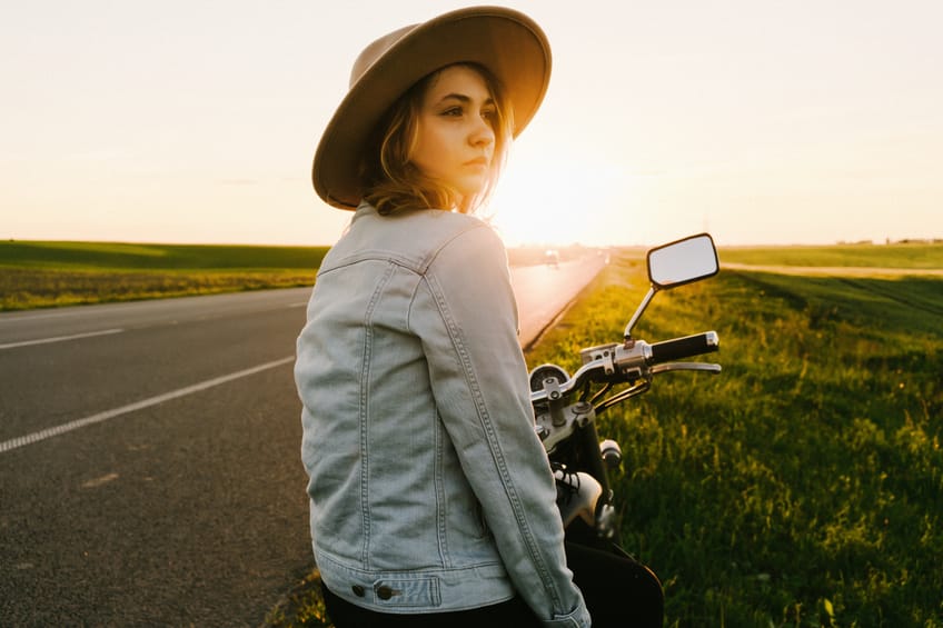 Woman sitting on the motorcycle at sunset