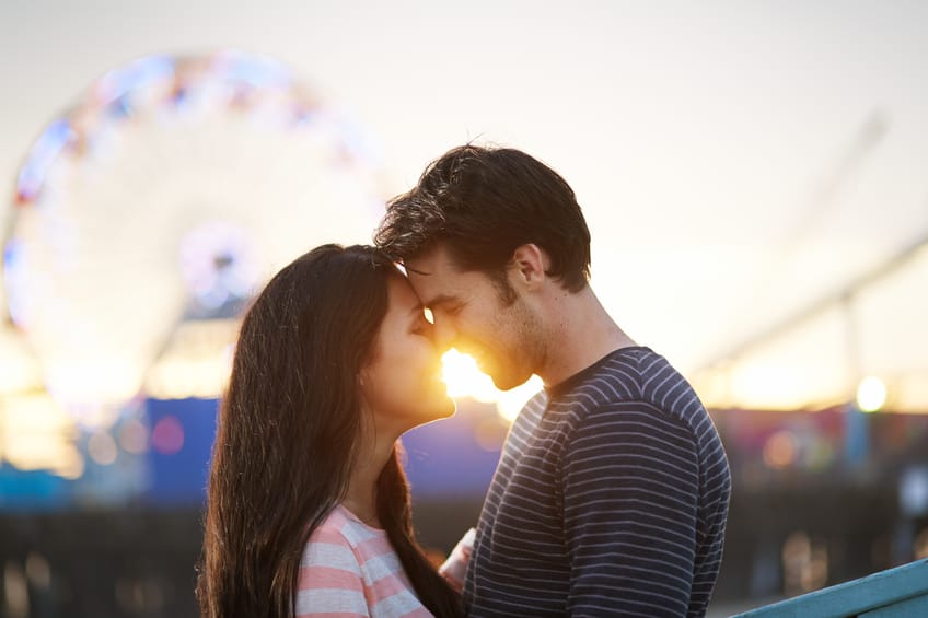 Smiling man and woman embracing at sunset at a carnival