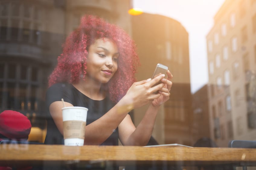 Beautiful girl in a cafe typing on smart phone