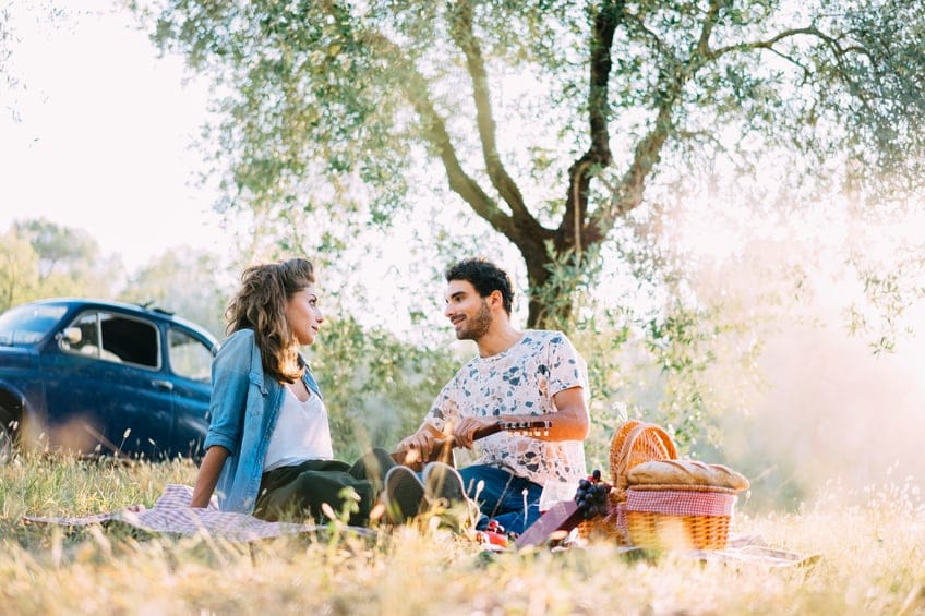 Young couple in love doing a picnic outdoors late afternoon