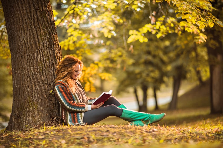Woman spending her free time in book reading outdoors.