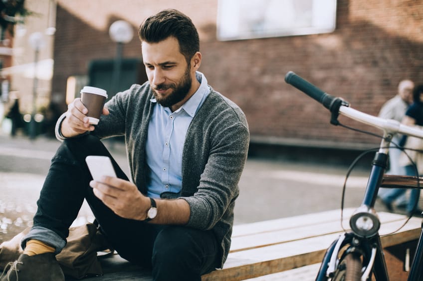 Man sitting on the bench and typing on his smart phone