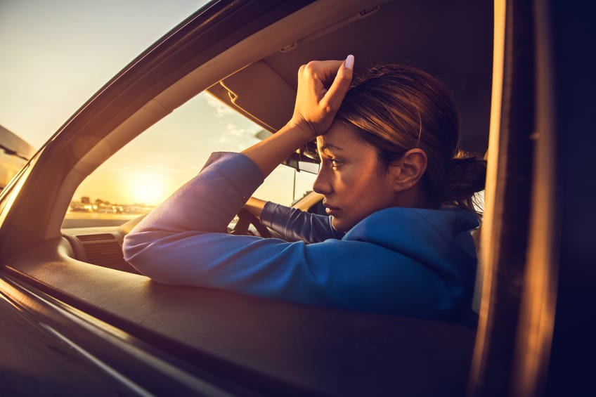 Sad businesswoman having problems while driving a car at sunset.