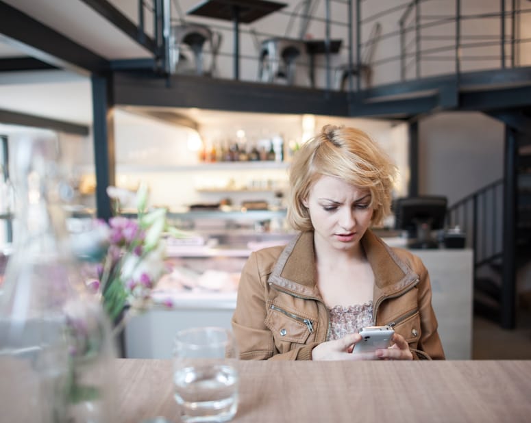 woman texting annoyed at cafe