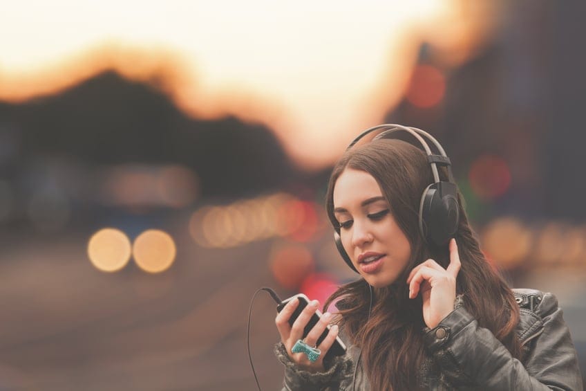 young woman headphones outside sunset