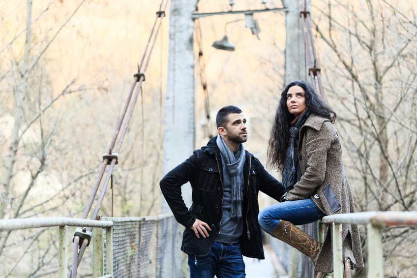 Young couple sad thinking sitting on bridge