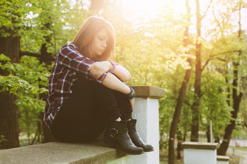 Unhappy girl outside sitting thoughtfully