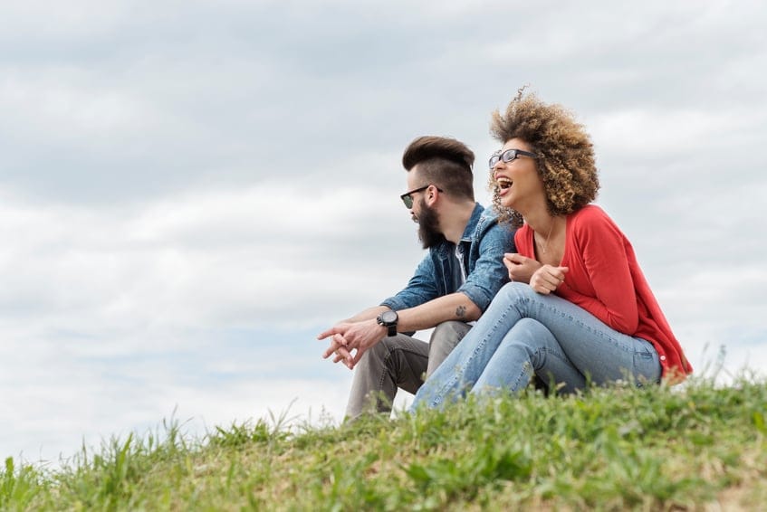 couple laughing happy grass hill outdoors