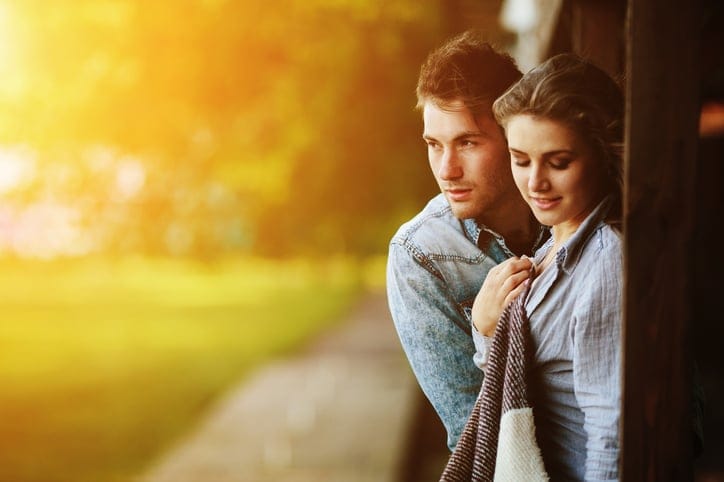Young couple in love wrapped in plaid standing and embrace
