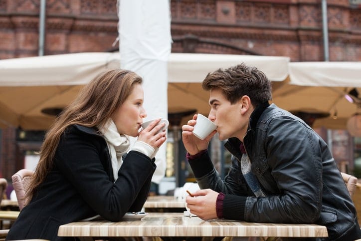 Side view of young couple drinking coffee together at outdoor restaurant