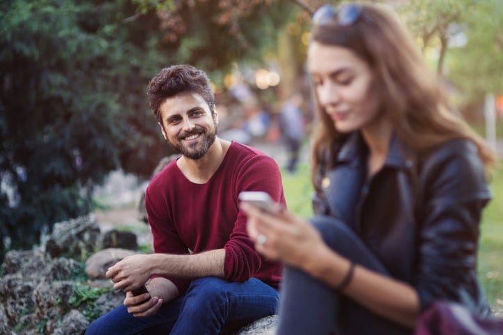 Young man smiling and looking at a girl in the park