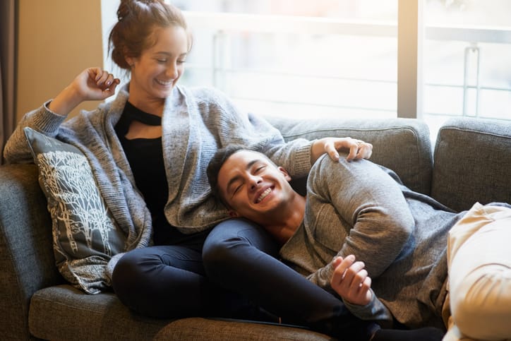 Portrait of a handsome young man lying on his girlfriend's lap on the sofa