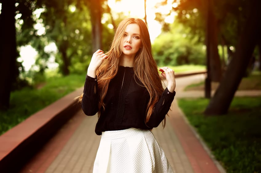 Charming young cute girl relaxing in the summer park, female student relaxing at campus, flare sun light.