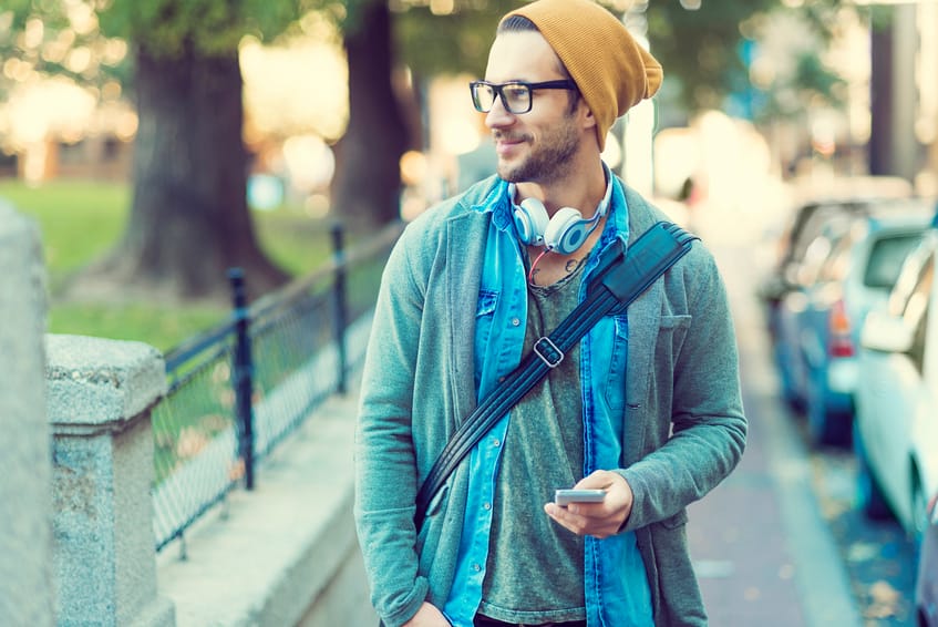handsome man walking in the street after work ,holding his smartphone