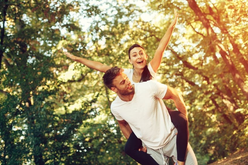 Young happy couple piggybacking in the park.
