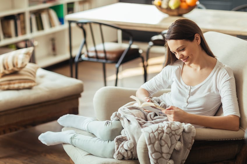 Photo of young beautiful woman reading book in armchair