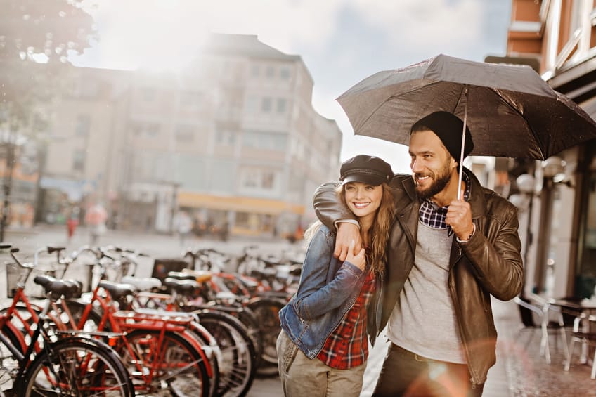 Close up of a happy young couple walking in the rain