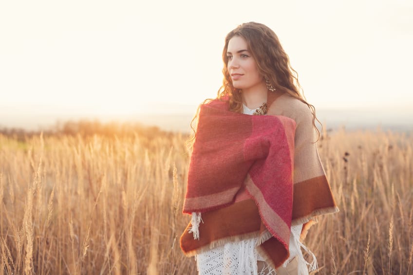Beautiful caucasian woman standing in the middle of a prairie, enjoying the peace and quiet of a nature.