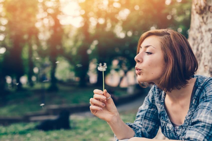 Girl in the park blowing a dandelion