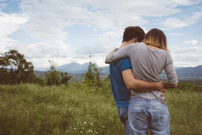 young couple hug field outdoors