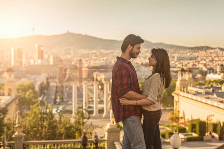 Loving young couple at sunset in Barcelona, they are embracing and looking each other.