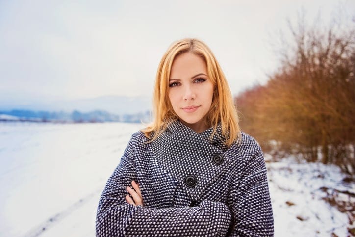 Beautiful blond woman in gray coat in winter nature