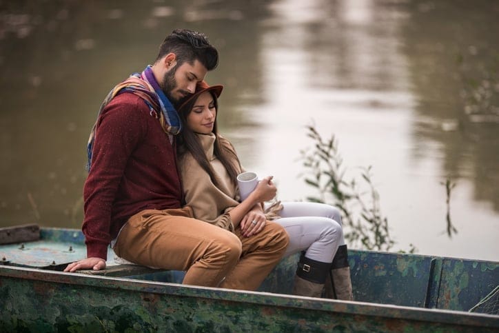 Young couple sitting in a boat during autumn day and relaxing with their eyes closed.