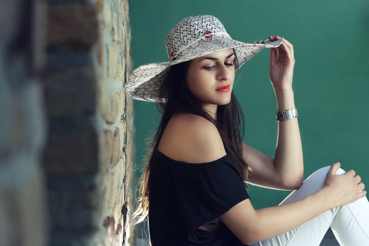 Young woman with straw hat leaning on the brick wall