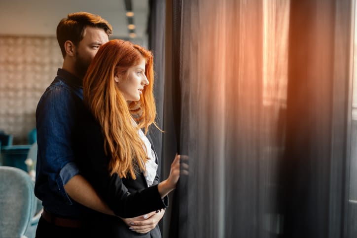 Romantic couple enjoying sunset from luxurious room