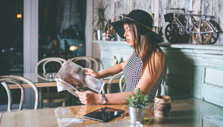 Woman reading the newspaper at a cafe.