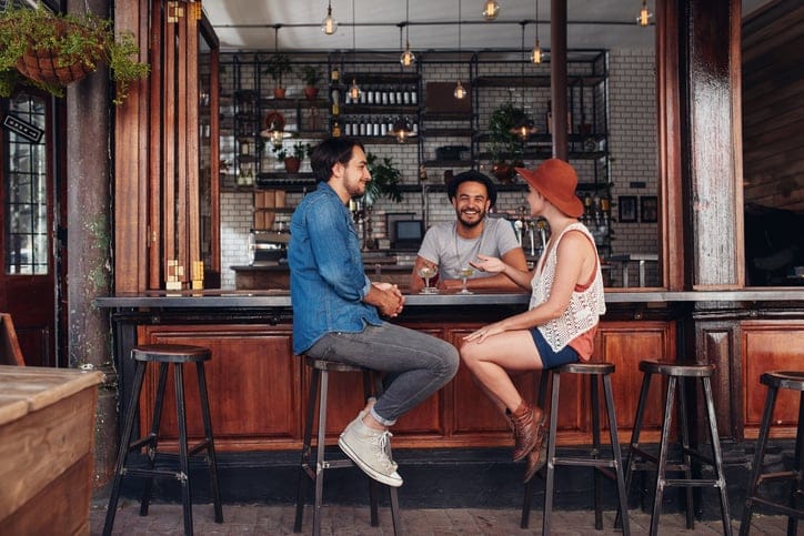 Group of young people sitting in a cafe and talking. Young men and women meeting at cafe table.