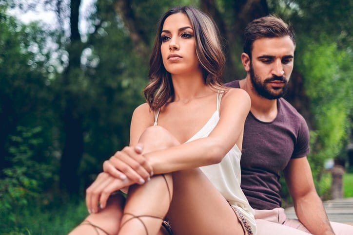 Sad couple sitting in the park and thinking