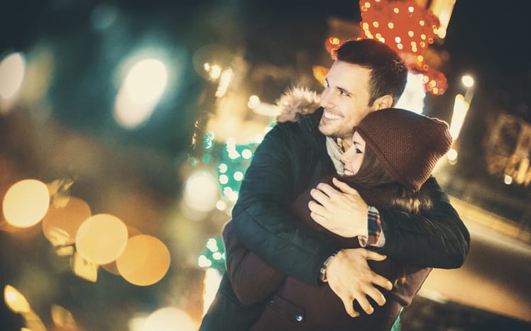Couple having a cuddle looking at Christmas lights
