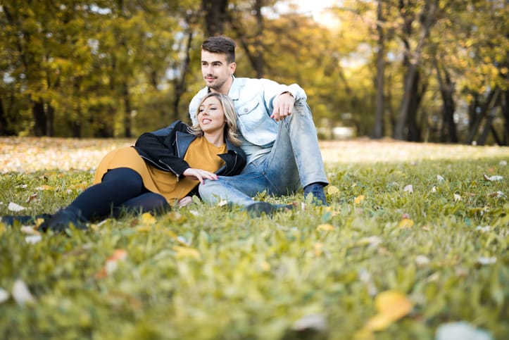 Happy young couple laying on the grass in the park