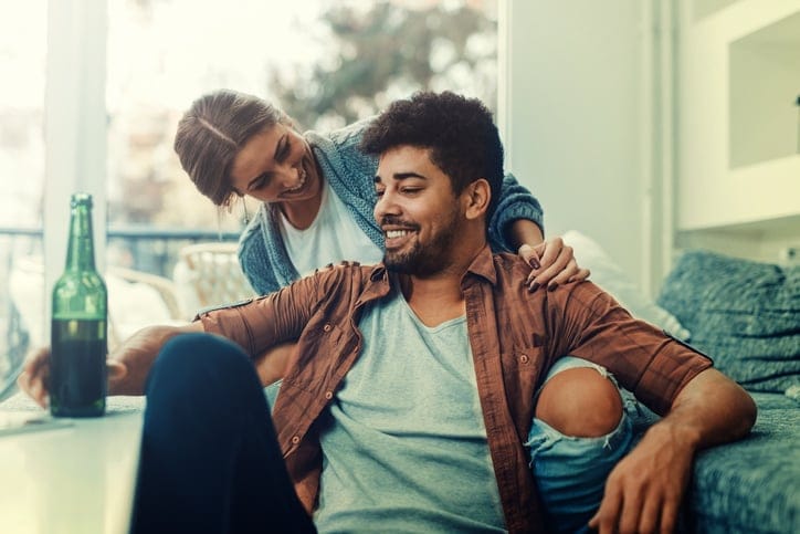 Young couple sitting on the bed in a living room and having fun together.