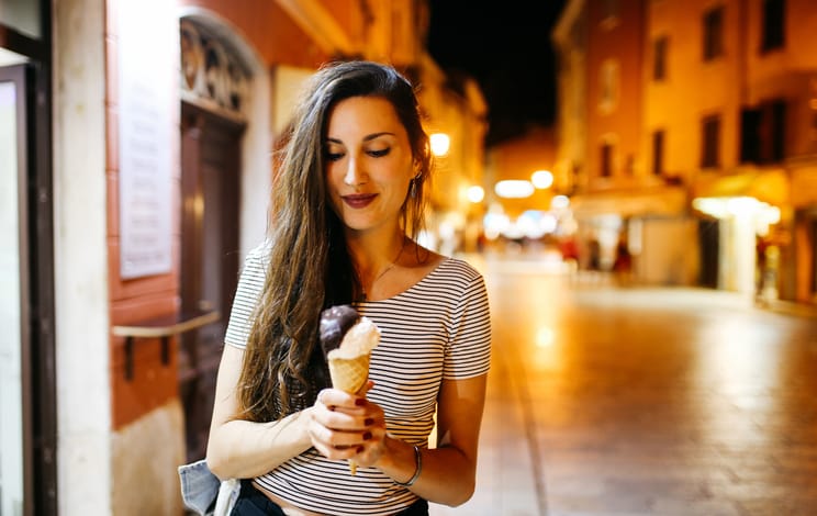 Young woman enjoying ice cream on the streets of Rovinj