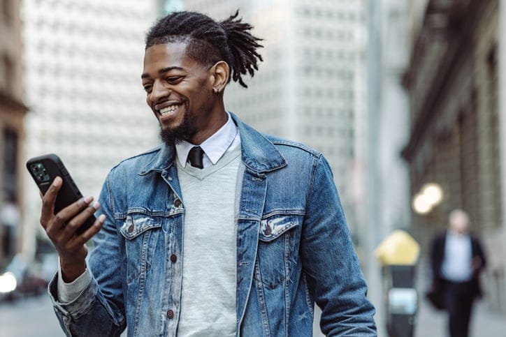 smiling guy texting walking city